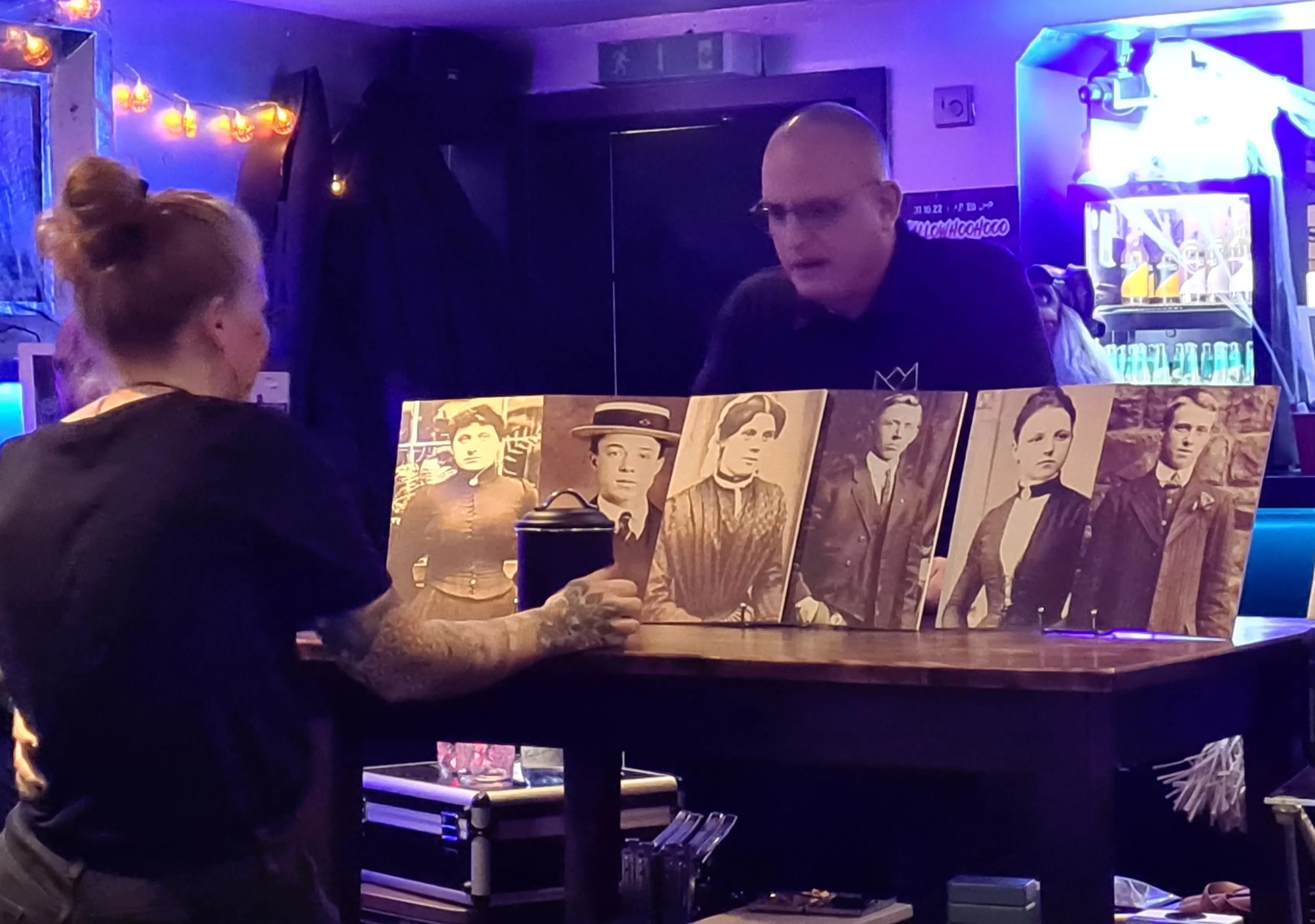 Joachim Jögel showing sepia portrait cards at a Halloween table lit by pumpkin lanterns