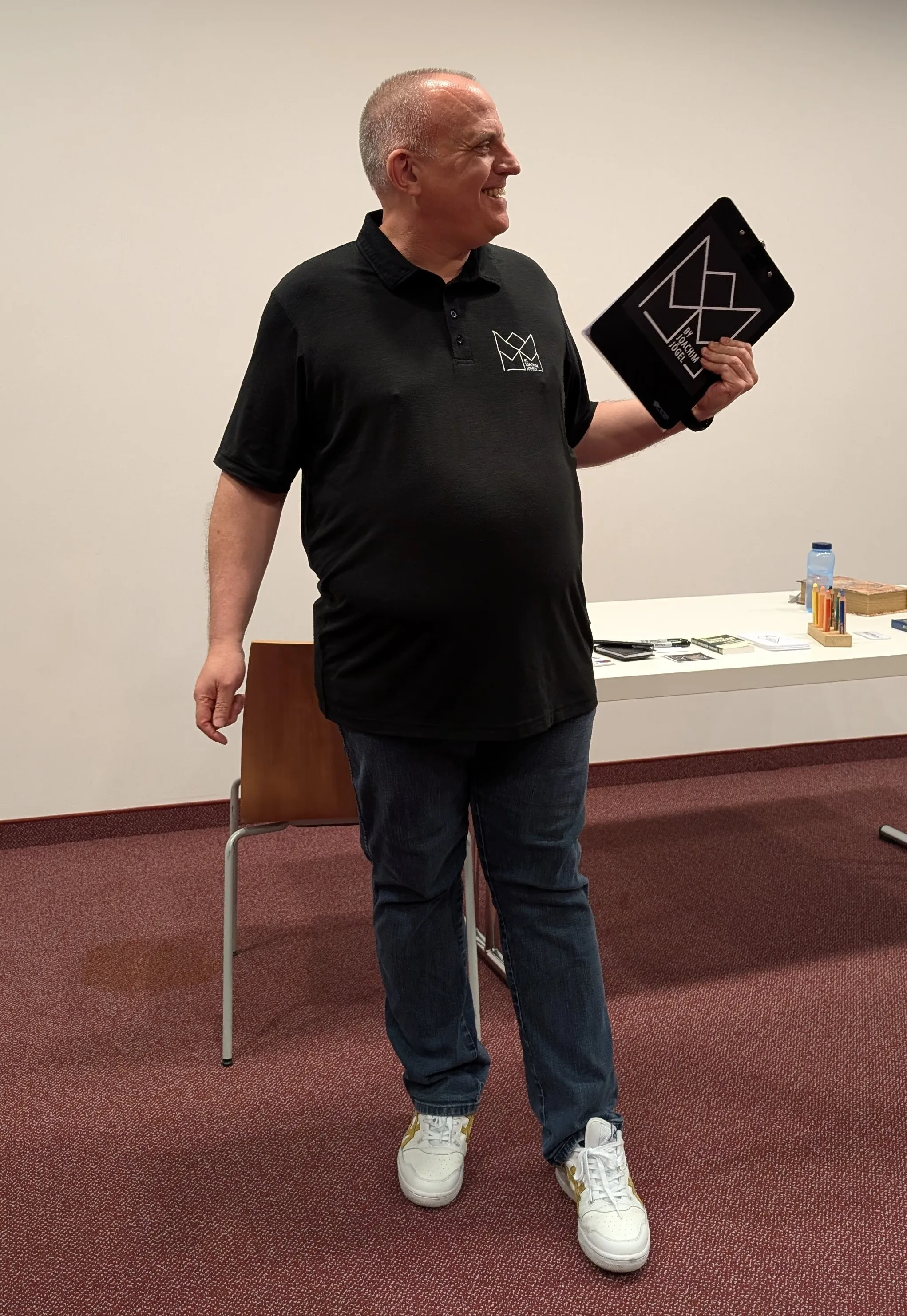 Joachim Jögel smiling, holding a clipboard prop
