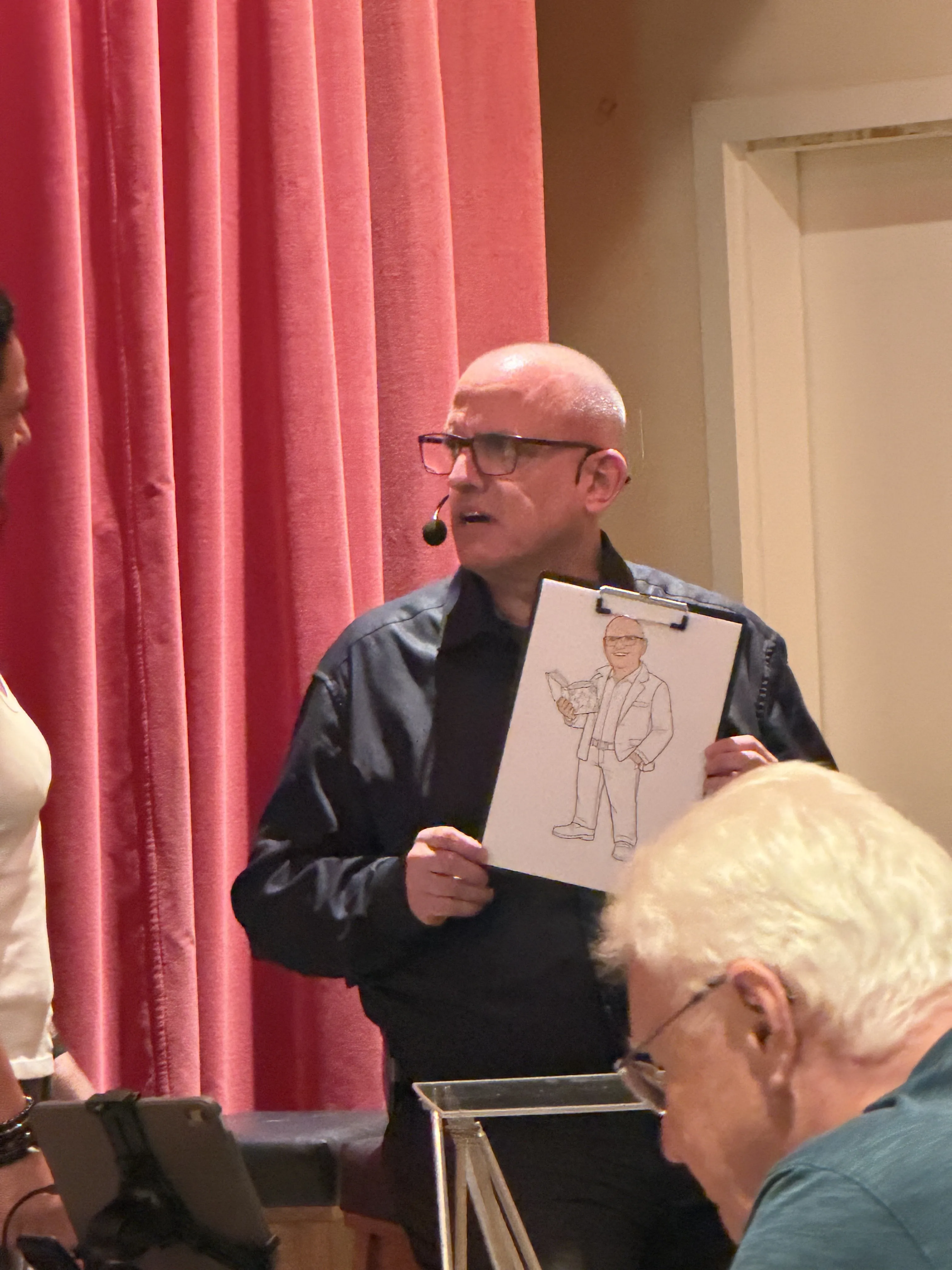 On stage, with a caricature of an audience member