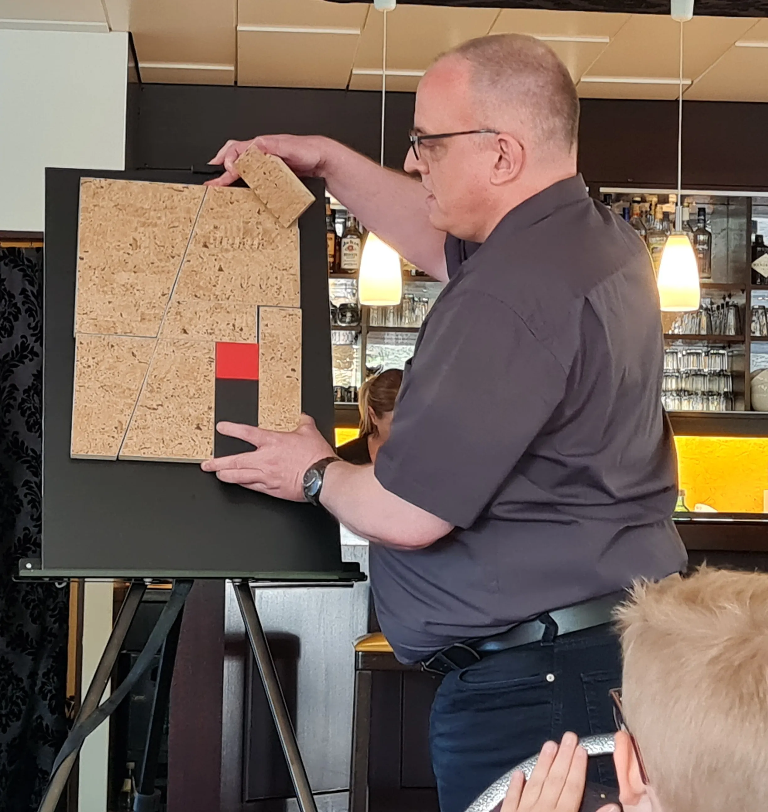 Joachim Jögel presenting “Puzzle des Lebens” on an easel in front of an audience
